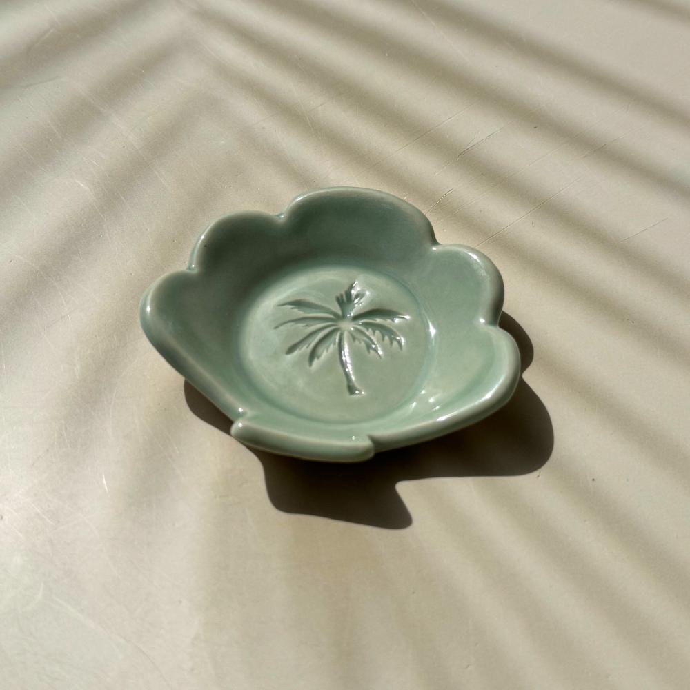 an aqua blue ceramic dish in the shape of a shell with palm tree